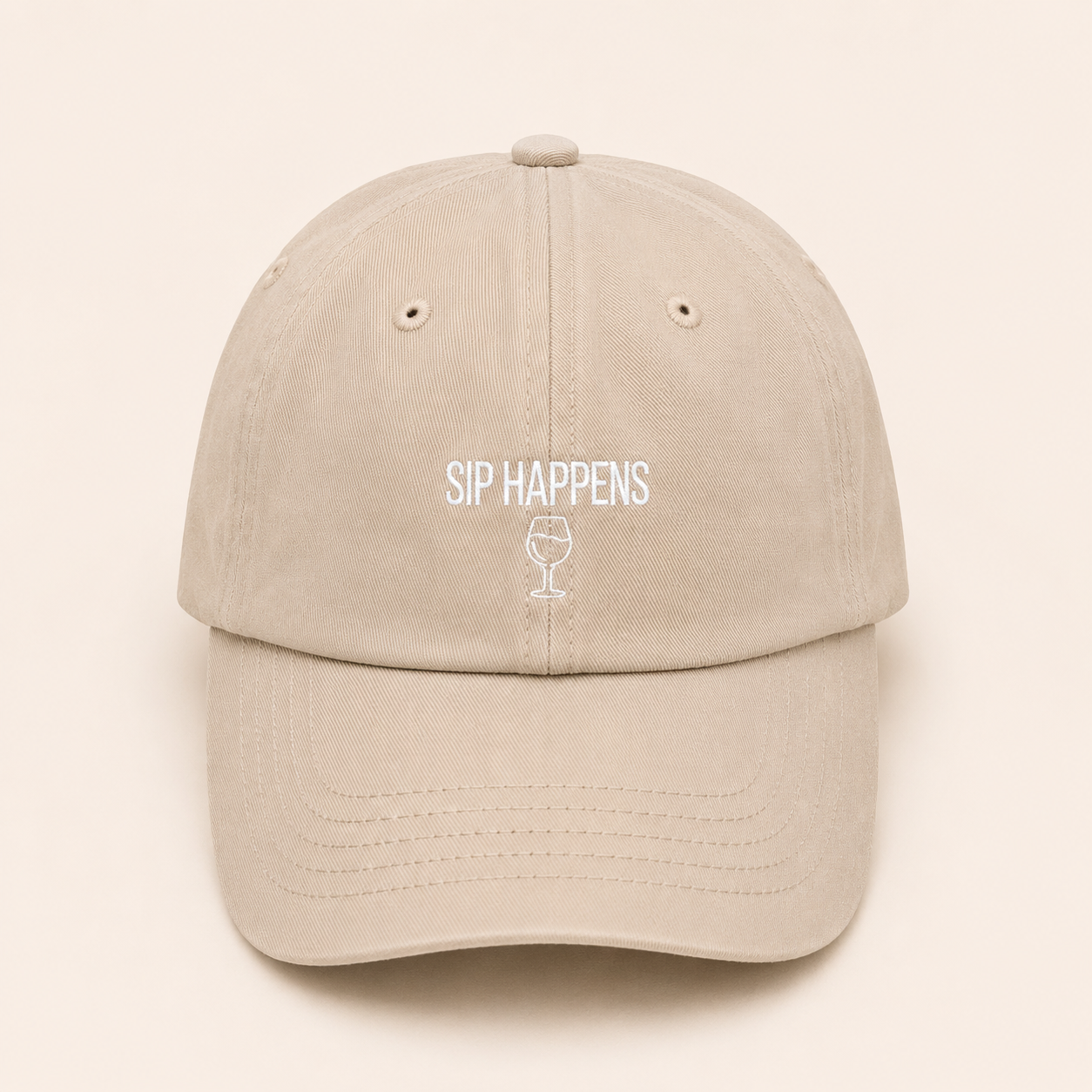 Beige cap with 'Sip Happens' text and wine glass icon on a beige background