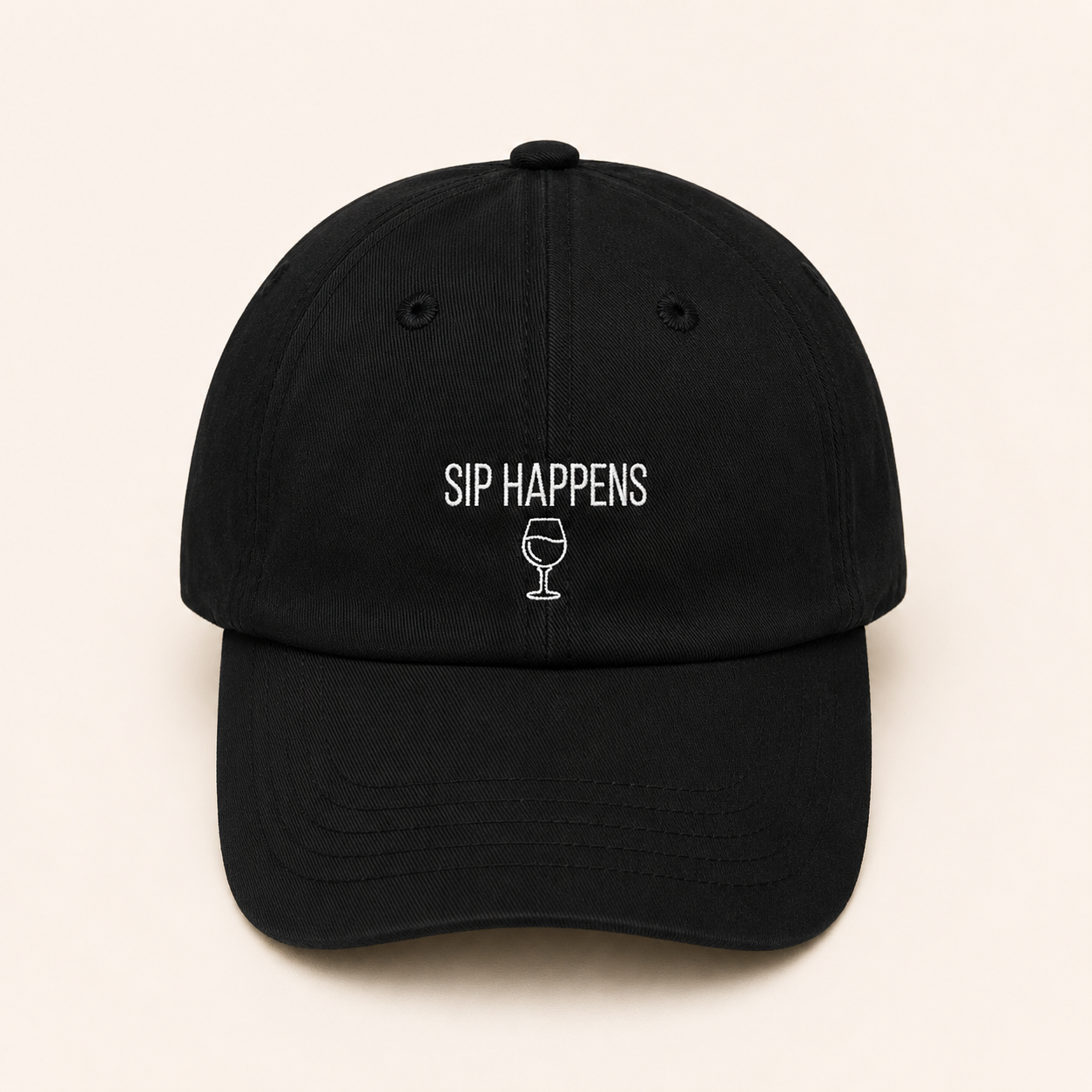 Black cap with 'SIP HAPPENS' text and wine glass icon on a beige background